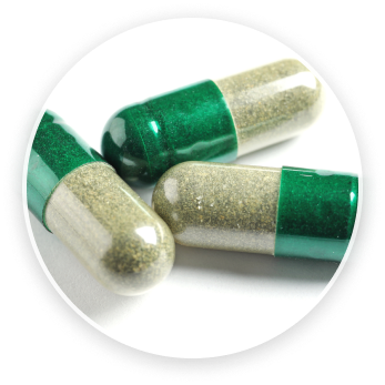 Zelené a biele kapsuly s výživovými doplnkami na svetlom pozadí.