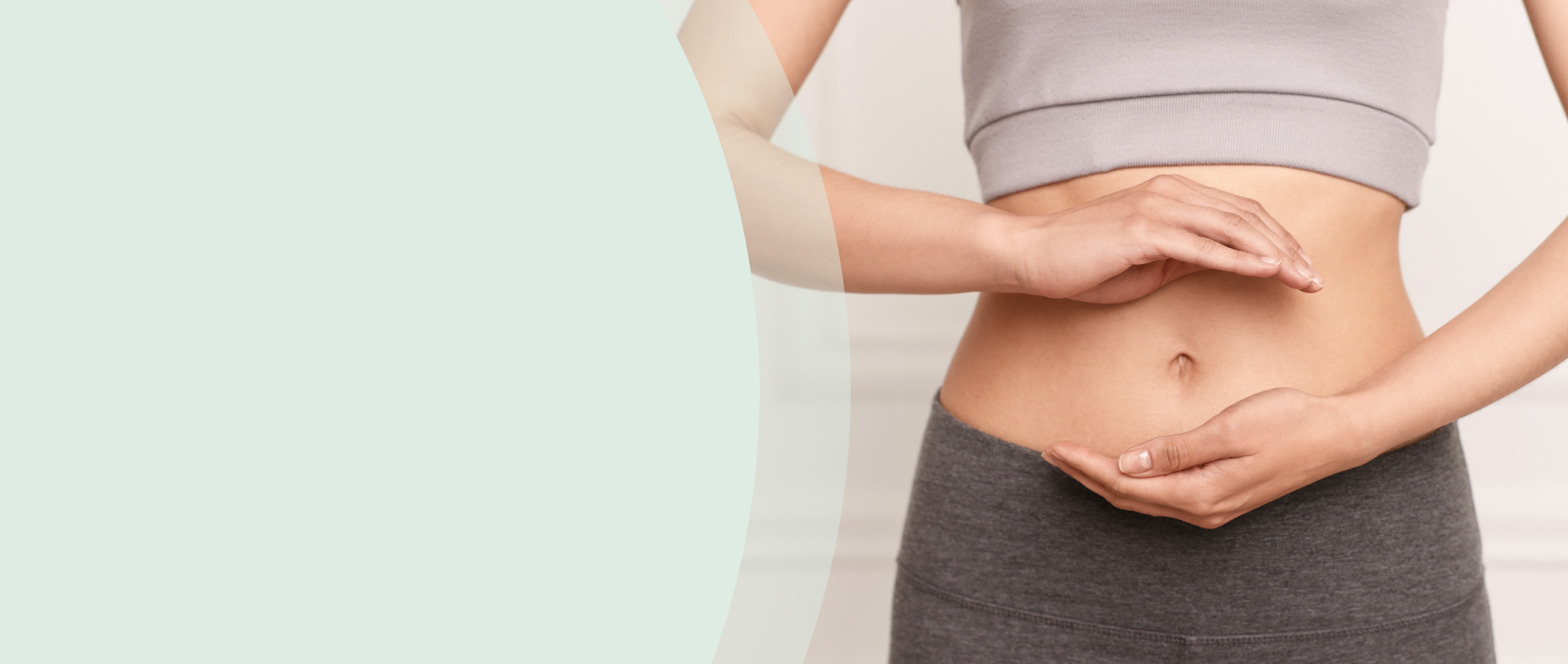 Žena si rukami drží oblasť brucha.