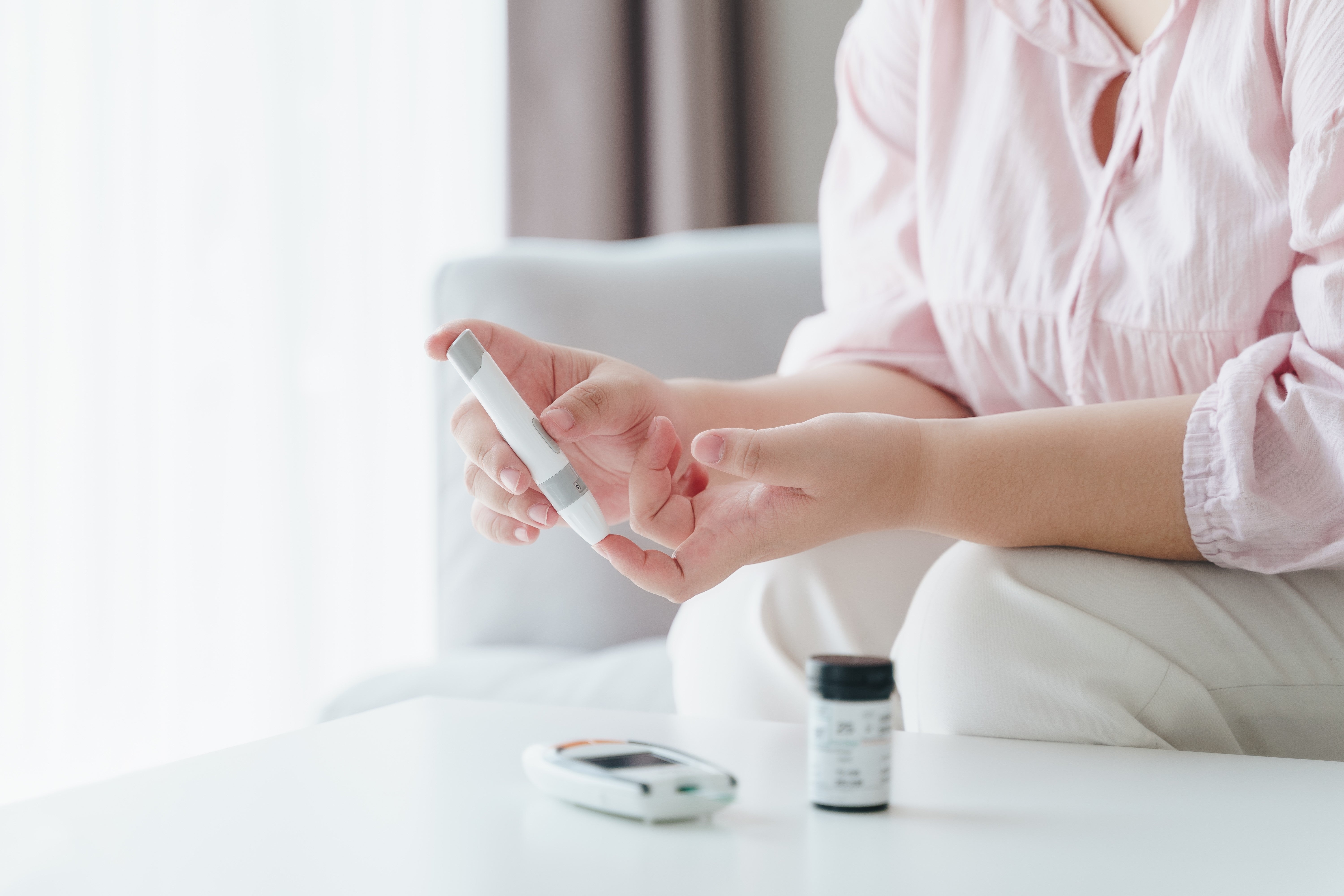 Osoba měří hladinu cukru v krvi pomocí glukometru.